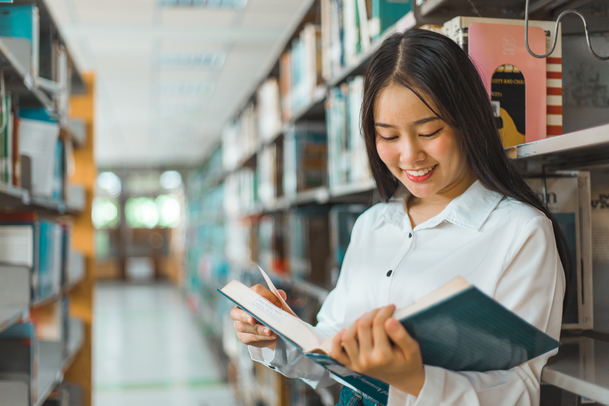 Female Student Reading a Book in a Library 